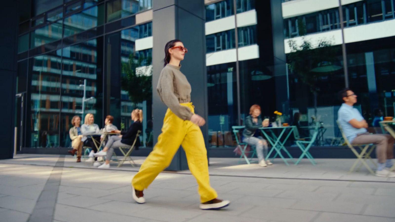 a woman walking down a sidewalk in front of a building