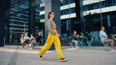 a woman walking down a sidewalk in front of a building