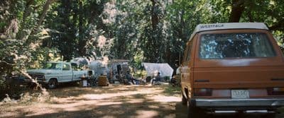 a couple of trucks parked next to each other in a forest
