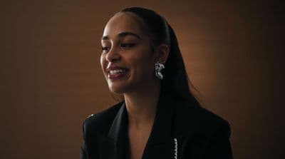 a woman wearing a black jacket and earrings