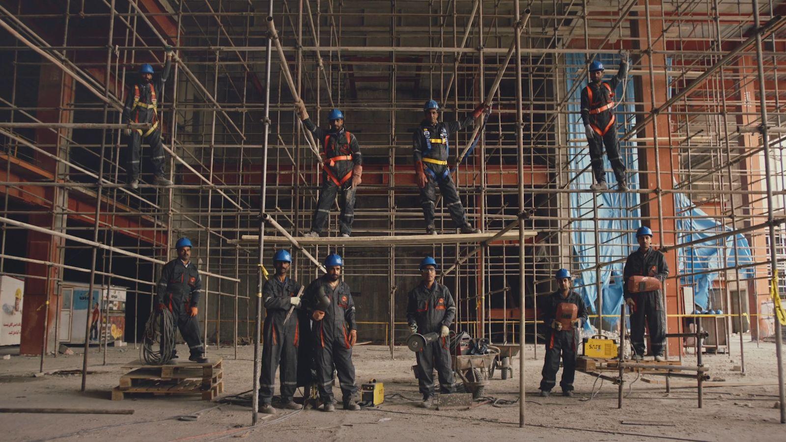 a group of men standing on top of scaffolding