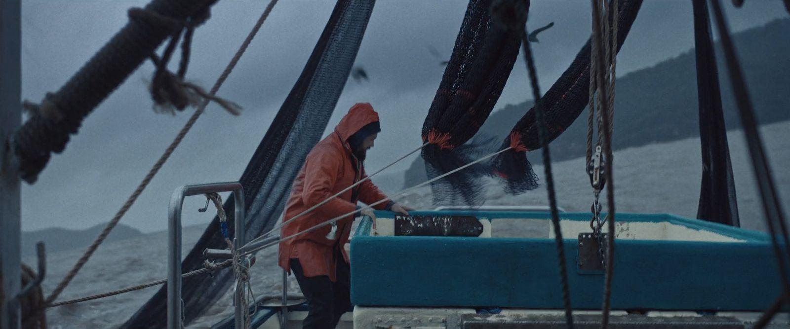 a man in a red raincoat standing on a boat