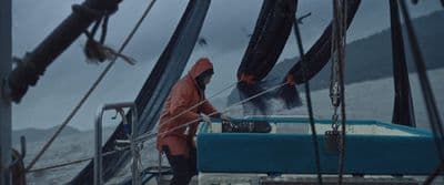 a man in a red raincoat standing on a boat