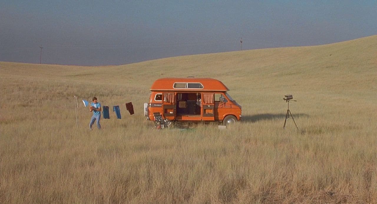 an orange food truck parked in a field
