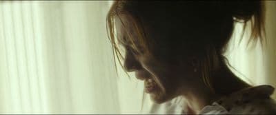 a woman with long hair standing in front of a window