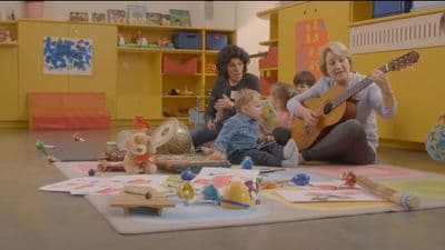 a woman playing a guitar with a group of children