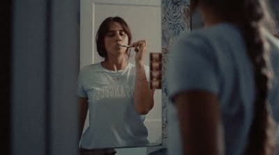 a woman standing in front of a mirror brushing her teeth