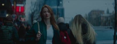 a woman with long red hair walking down a street