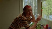 a woman with red hair standing in front of a window