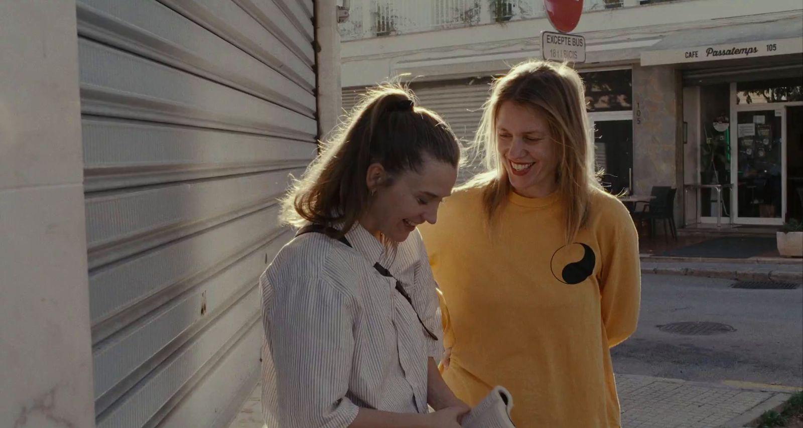 two women standing next to each other near a building