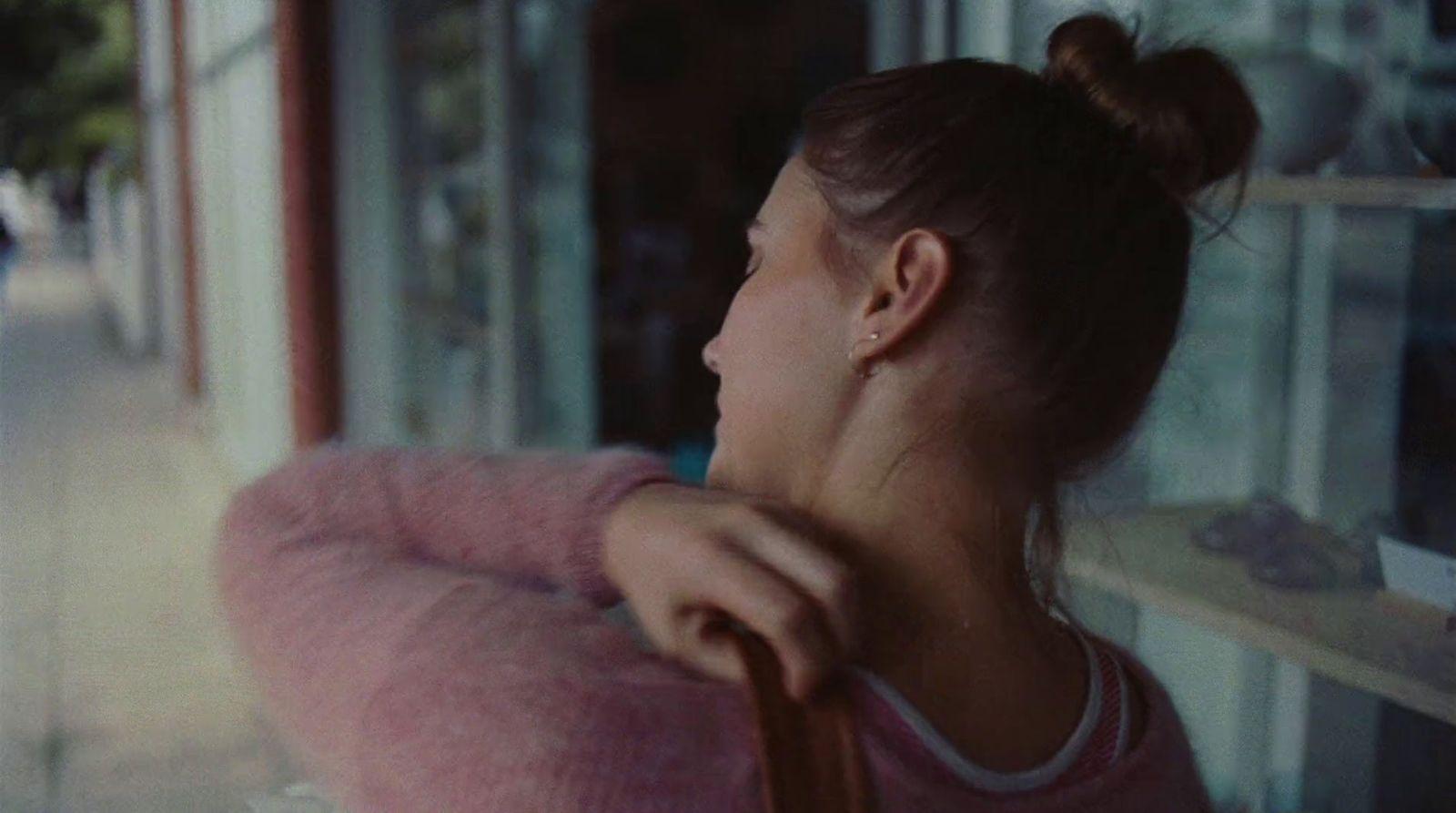 a woman in a pink sweater looking out a window