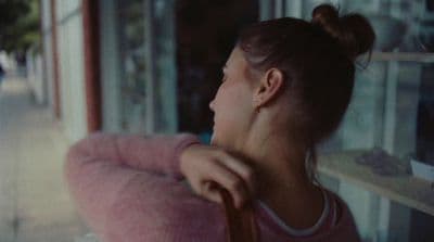 a woman in a pink sweater looking out a window