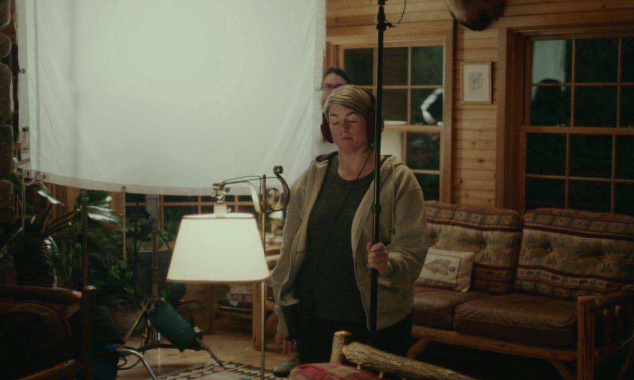 a woman standing in a living room next to a lamp
