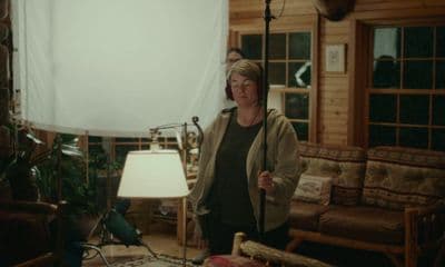 a woman standing in a living room next to a lamp