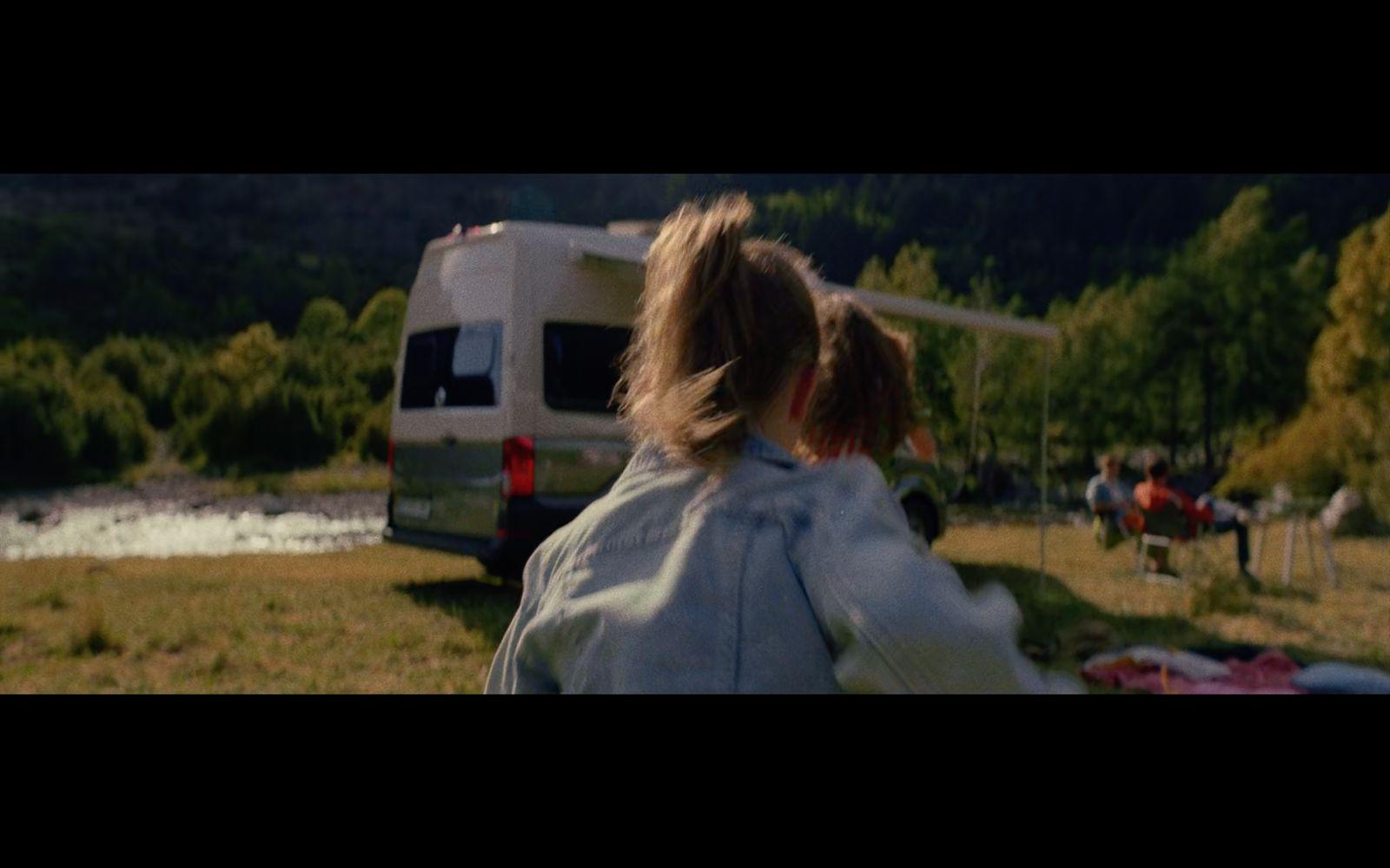 a woman standing in a field next to a camper
