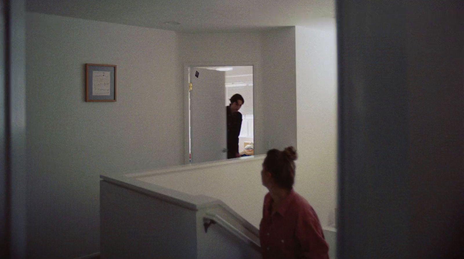two women standing in a hallway looking at a mirror