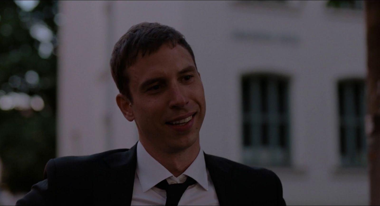 a man in a suit and tie standing in front of a building