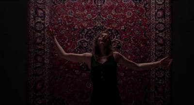 a woman standing in front of a rug with her arms outstretched