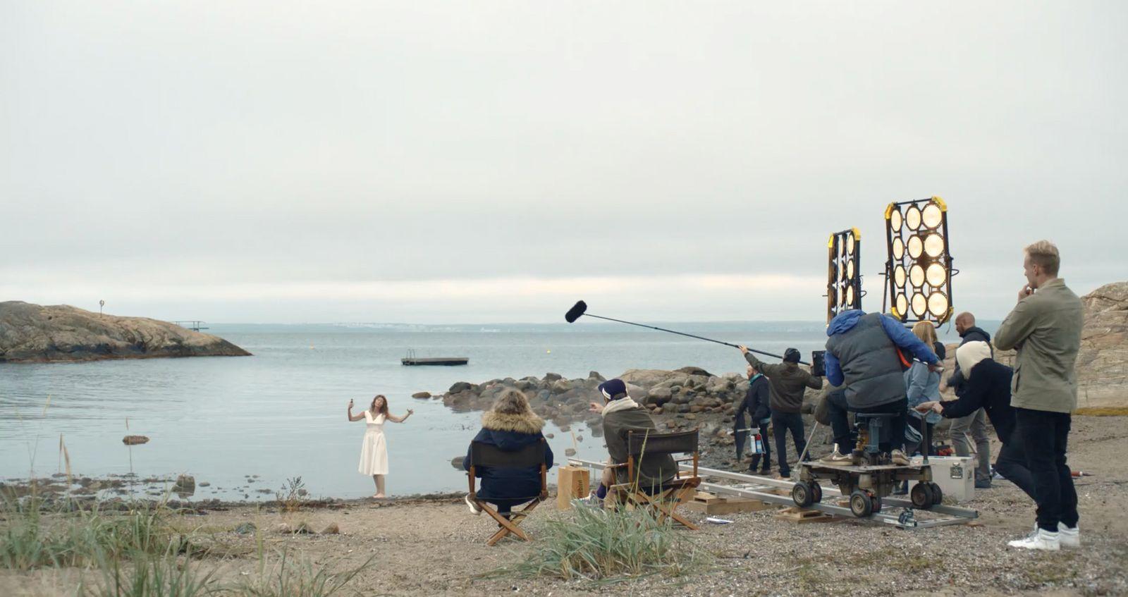 a group of people standing on top of a beach next to a body of water