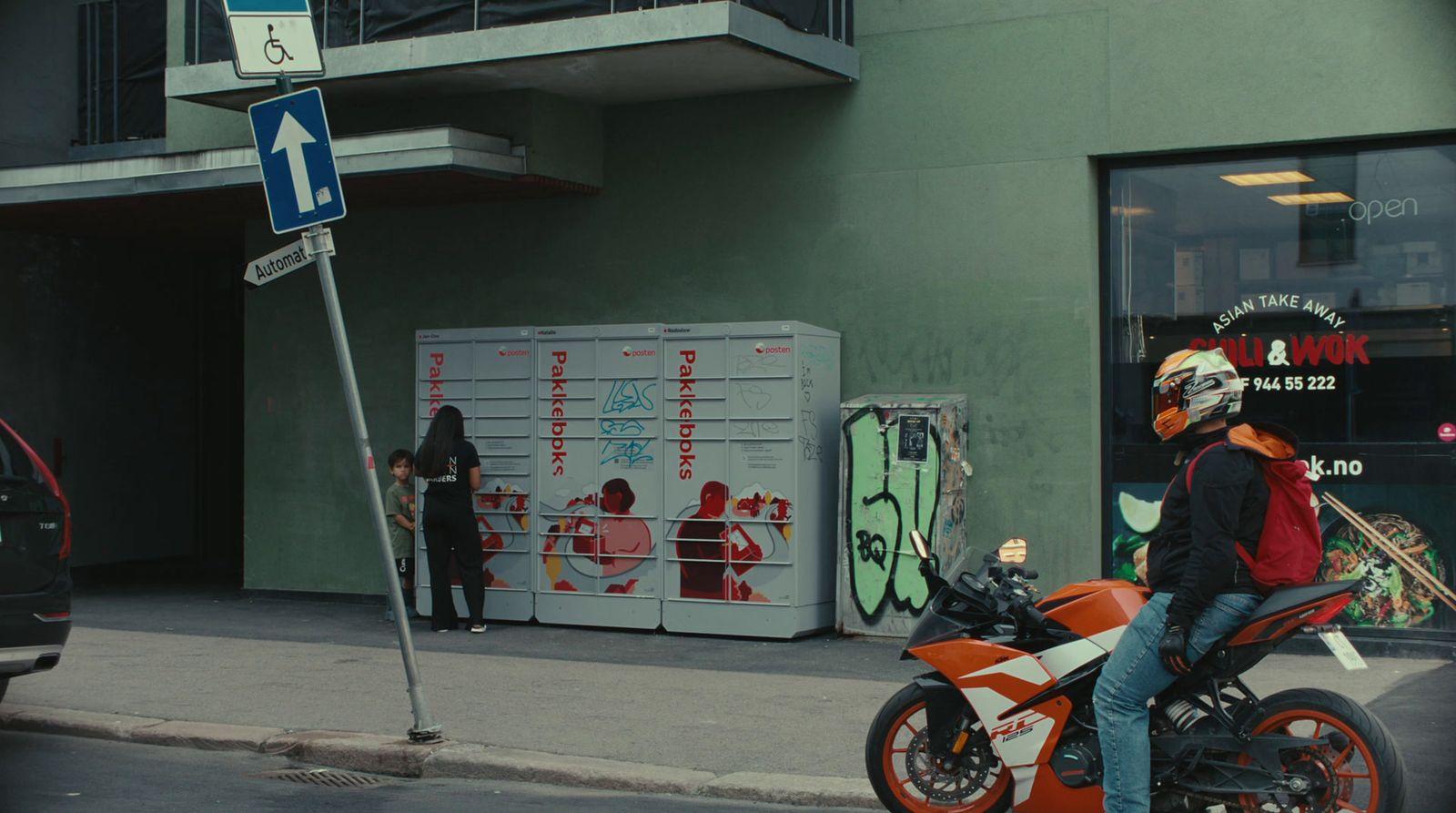 a man riding a motorcycle down a street next to a tall building