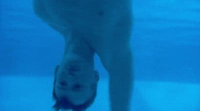 a man standing under water in a swimming pool