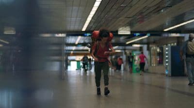a woman walking through a terminal holding a cell phone