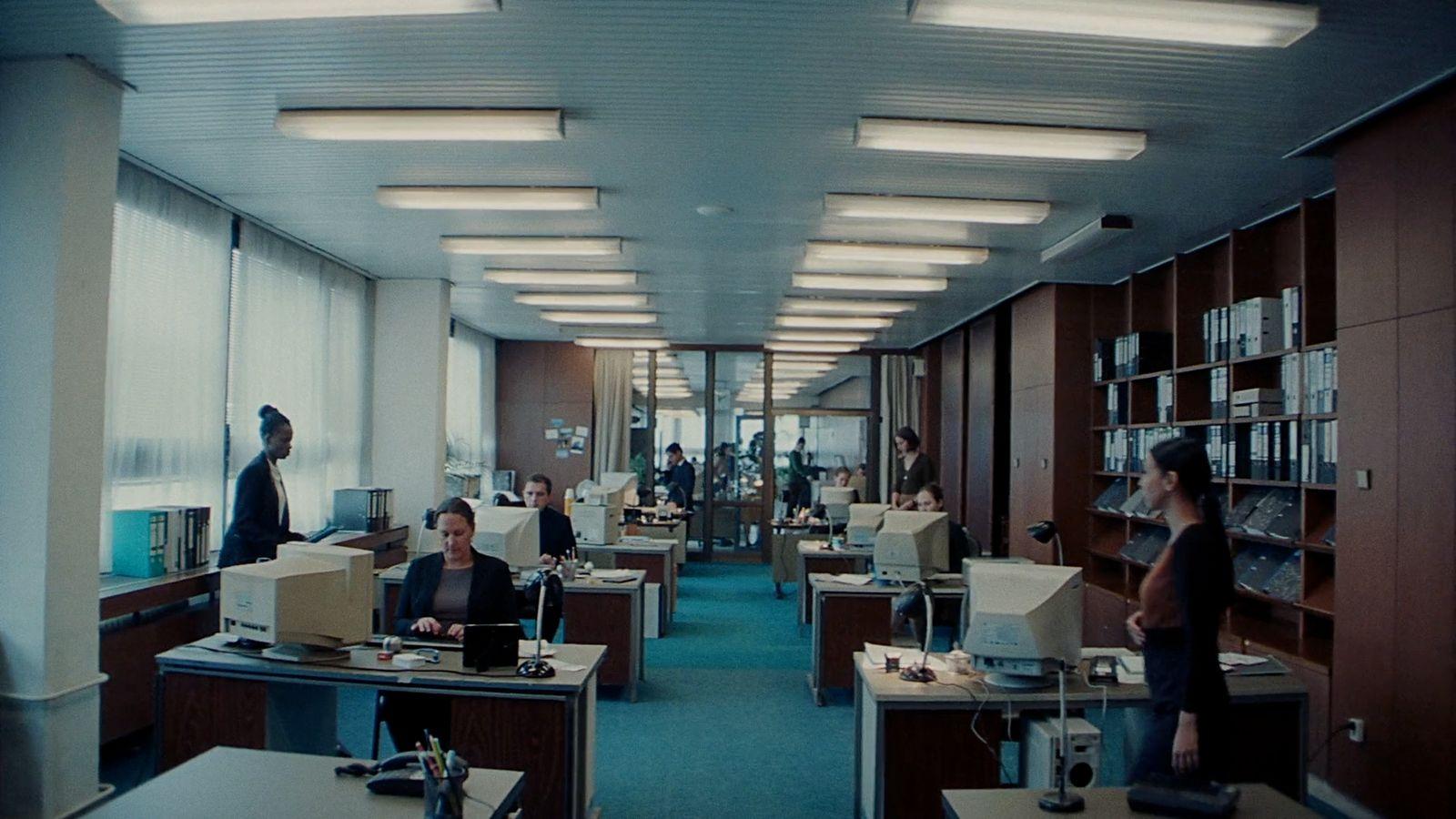 a group of people sitting at desks in an office
