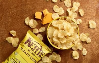 a bag of kettle chips next to a bowl of cheetos