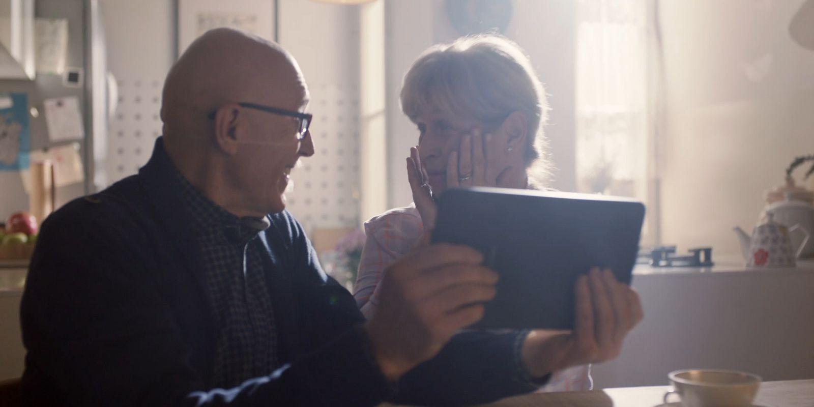a man and woman sitting at a table looking at a tablet