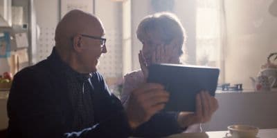 a man and woman sitting at a table looking at a tablet