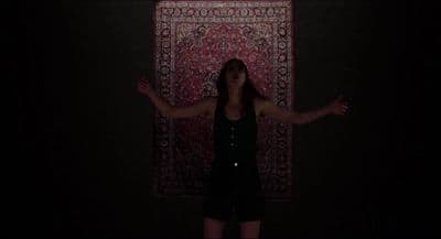 a woman standing in front of a rug in the dark