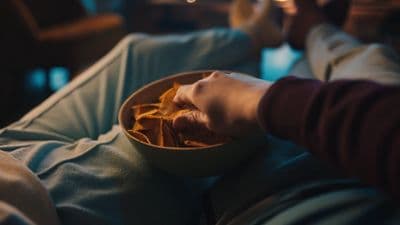 a person holding a bowl of chips on a couch