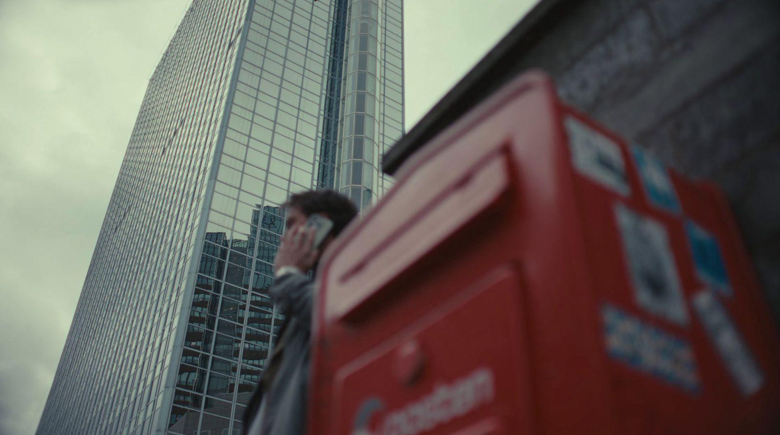 a man talking on a cell phone in front of a tall building