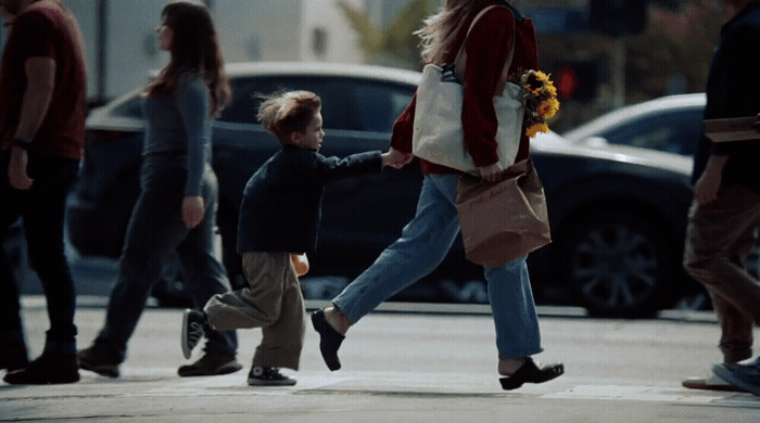 a woman holding a child's hand as they cross the street