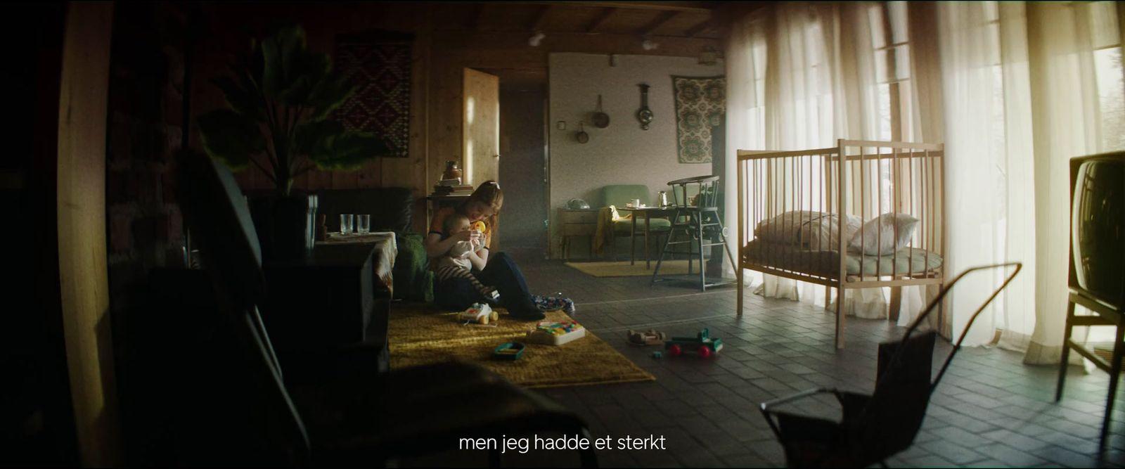a woman sitting in a living room next to a baby crib