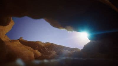 a view of the sun through a hole in a rock