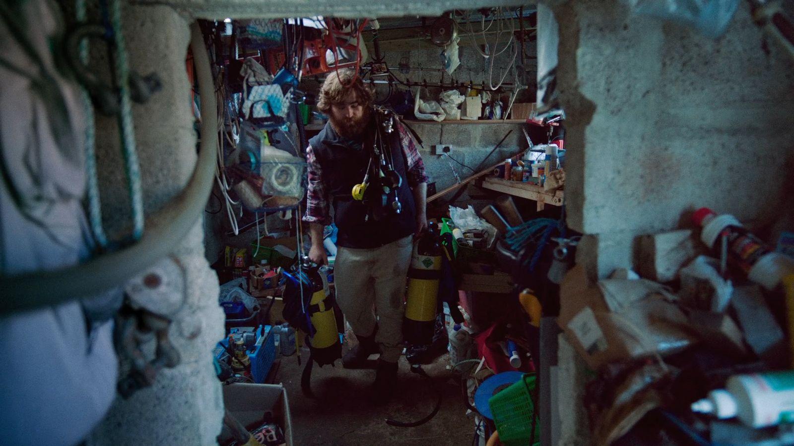 a man standing in a room filled with lots of clutter