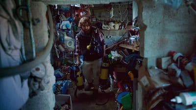 a man standing in a room filled with lots of clutter