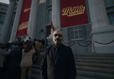 a man in sunglasses standing in front of a building