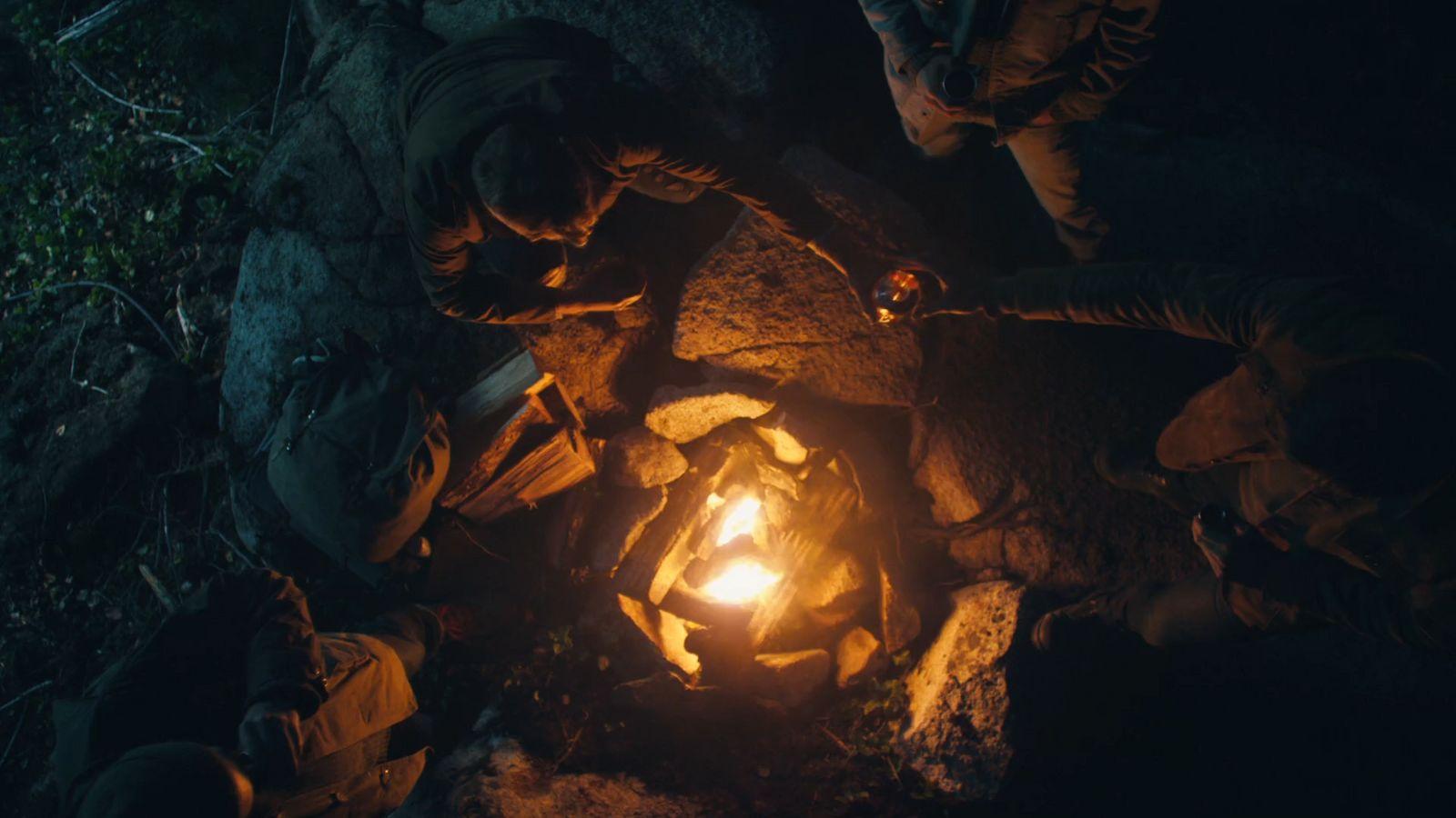 a group of people standing around a fire pit