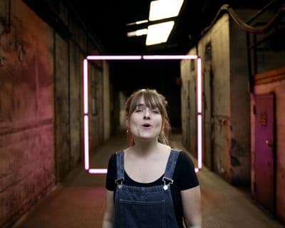 a woman standing in a hallway with a neon frame