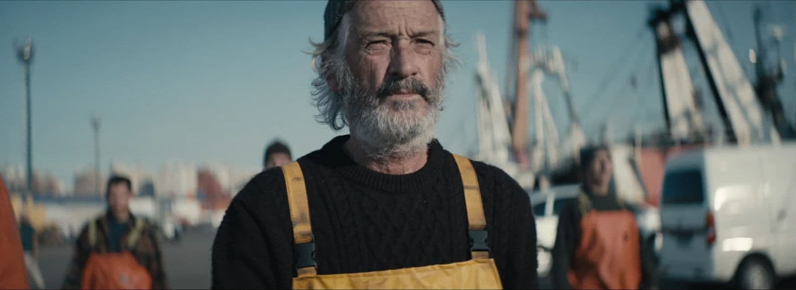 a man with a beard wearing overalls and a sweater