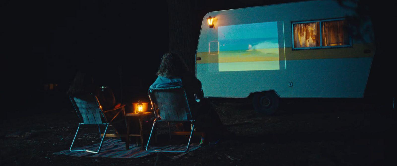 a woman sitting in a chair in front of a camper