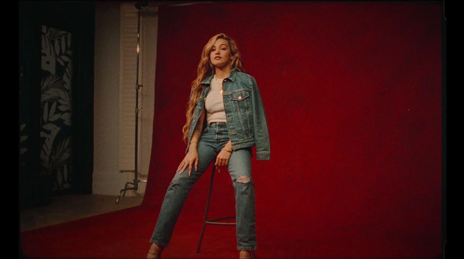 a woman standing on a stool in front of a red wall