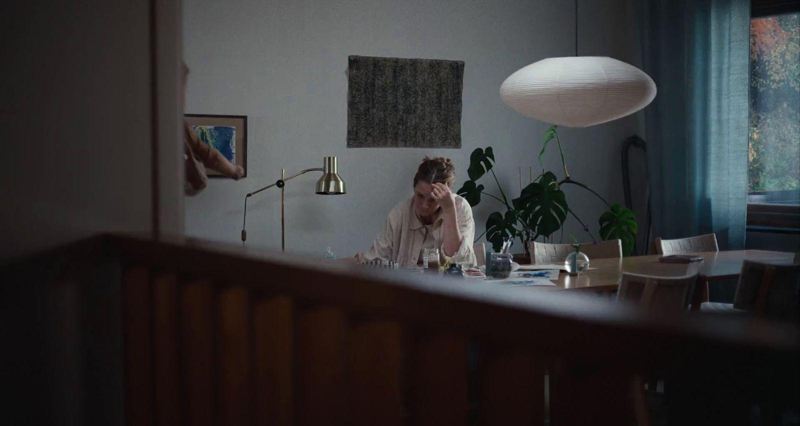 a woman sitting at a table in front of a lamp