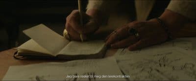 a person sitting at a table writing on a piece of paper