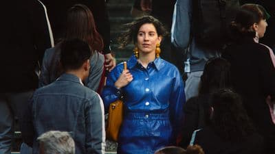 a woman in a blue shirt and yellow earrings