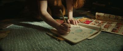 a person is writing on a notebook with a pen