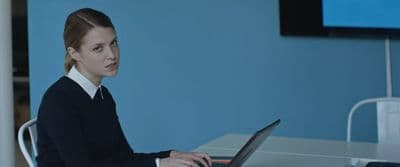 a woman sitting at a table using a laptop computer