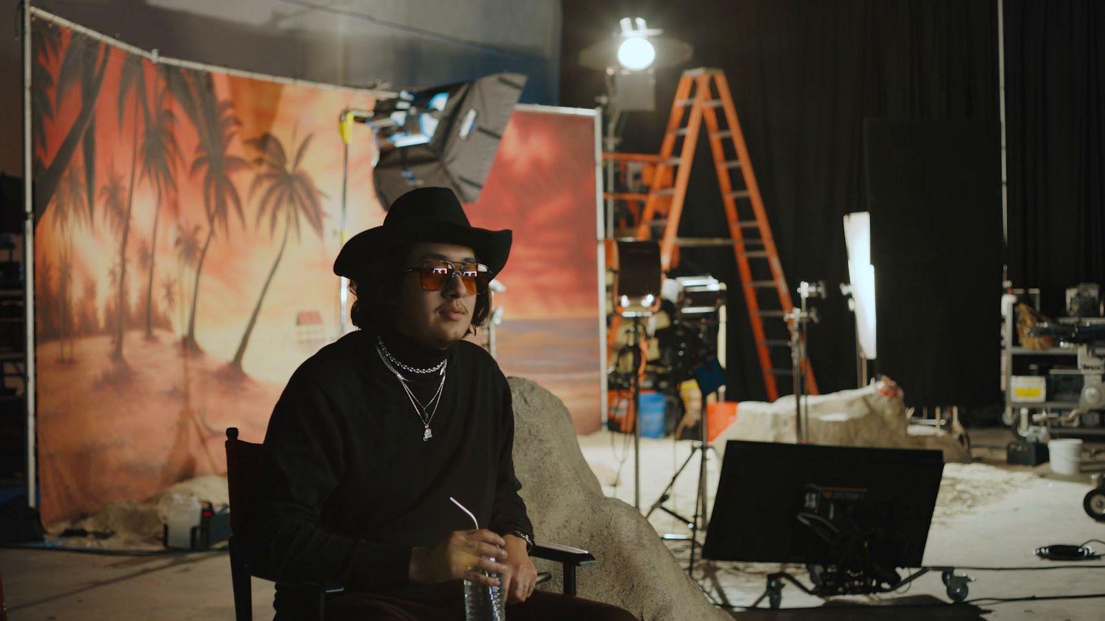 a man sitting in a chair in front of a backdrop